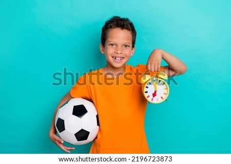 Photo of pretty funky small man wear yellow t-shirt smiling holding ball rinsing clock isolated turquoise color background