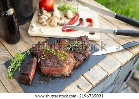 Grilled beef steak on wooden table top. Healthy food concept. Beef cut outdoors, garden kitchen, grill patio