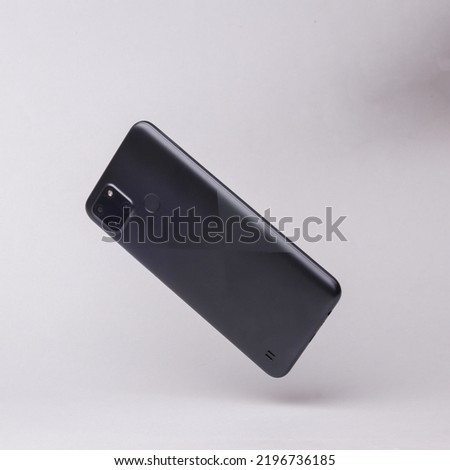 Modern smartphone backside with camera flying in antigravity on gray background with shadow. Levitation object in the air. Creative minimal layout Royalty-Free Stock Photo #2196736185