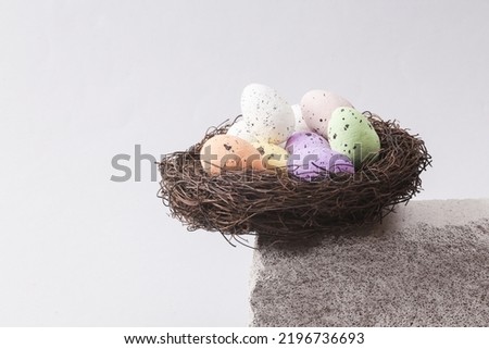 Minimalistic Easter composition with colored eggs in a nest on a stone