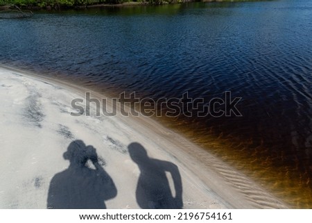 Shadows of a man and a woman on the beach sand by the water. Praia do Guaibim, coast of the sea of Bahia, Brazil