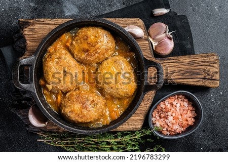 Fish balls with tuna in tomato sauce in a pan. Black background. Top view.
