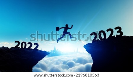 New year concept of 2023. New year's card. Silhouette of a man jumping over a cliff. Royalty-Free Stock Photo #2196810563