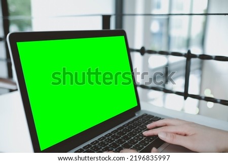 asian young businessman working on laptop with blank green screen in coffee shop.