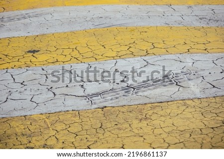 Marking of the pedestrian crossing on asphalt, yellow zebra crossing background texture with tyre marks