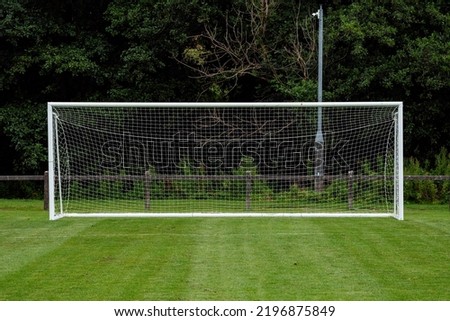 Side of football of soccer goal post with net in focus. Field out of focus. Sport background and equipment. Front view.