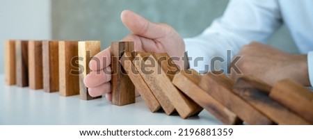 insurance with hands protect domino. Businessman hands stop dominoes falling in business crisis. business risk control and planning and strategies to run prevent insurance businesses. Royalty-Free Stock Photo #2196881359