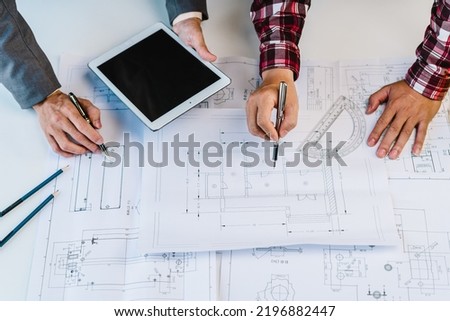 Two man Architect engineer discussing about blueprints at desk in office.