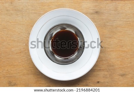 a cup of black coffee with a clear glass cup and a white plate cistern.  Picture taken with high angle
