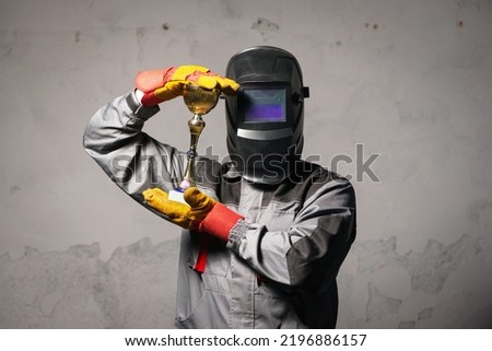 Welder with the golden cup award trophy in hands close up. Best welder of the year.