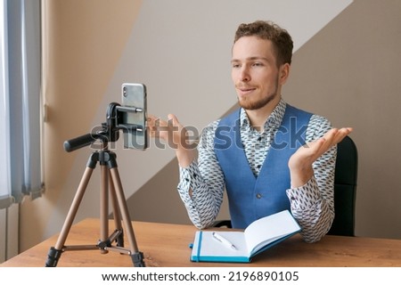 Social media influencer or blogger in fis content creation, video conference online using smartphone on tripods and lavalier, smiling content creator Vlogger