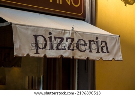 A Pizzeria Awning with the word pizzeria on a facade of a restaurant.