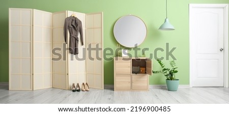 Interior of stylish hallway with folding screen and mirror 