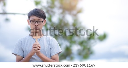 Young man in glasses holding christian pray to God. Concept religion. Focus on face. Copy space for your individual text.