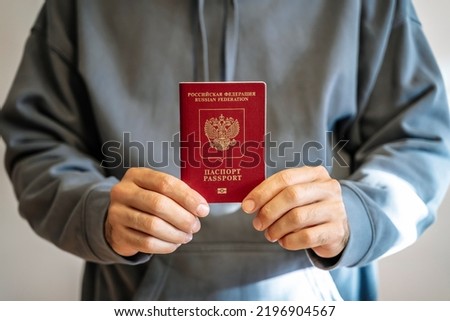 Russian passport in the hands of a man. Prohibition of Schengen visas for Russian tourists to travel to the European Union concept. Royalty-Free Stock Photo #2196904567