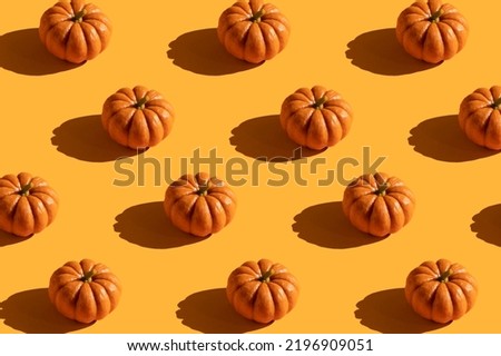 Pattern of pumpkins with shadows on orange background.