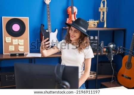 Young woman musician making selfie by smartphone at music studio