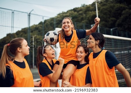 Happy women's soccer team carrying one of the players while celebrating wining the match on playing field. Royalty-Free Stock Photo #2196932383