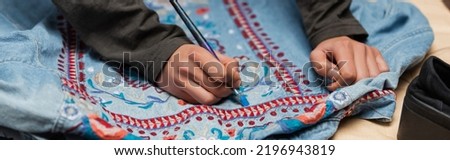 Cropped view of african american craftswoman painting on denim jacket with embroidery, banner