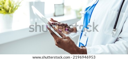 Woman doctor using tablet computer while standing straight in hospital. Female doctor using his digital tablet in the consultation. Medicine and healthcare concept. 