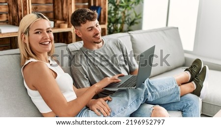 Young caucasian couple smiling happy using laptop sitting on the sofa at home.