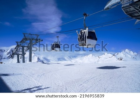 Funitel aerial lift in snow mountains against blue sky with clouds in bright winter day