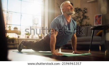 Strong Athletic Fit Senior Man Training on a Yoga Mat, Doing Back Stretching and Core Strengthening Exercises During Morning Workout at Home in Sunny Apartment. Concept of Health and Fitness. Royalty-Free Stock Photo #2196961357