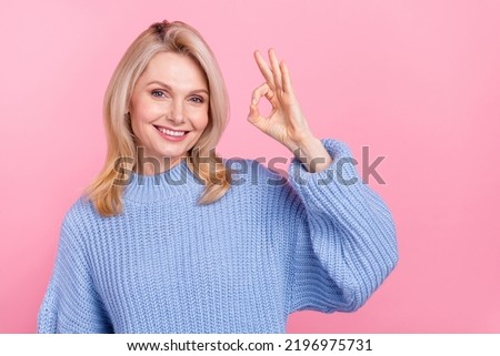 Photo of mature nice blond lady show okey wear blue pullover isolated on pink color background