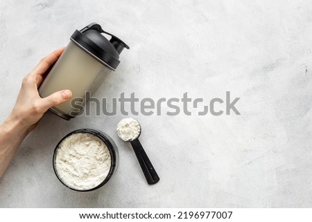Sport shaker bottle in hands and whey protein in jar. Fitness and gym diet nutrition Royalty-Free Stock Photo #2196977007
