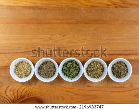 dried  herbs for Mediterranean cooking in white bowls on a wooden table  background