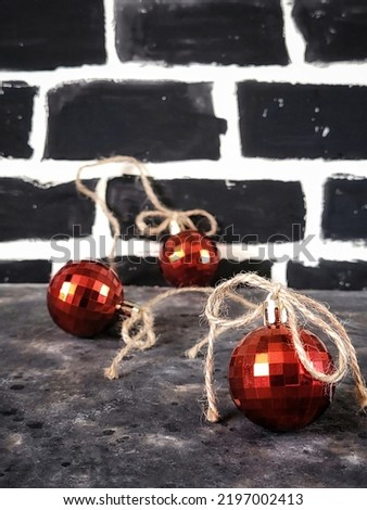 Atmospheric still life in a rustic style with red disco christmas balls on a black brick wall background with copy space. Christmas concept. New year greeting card.