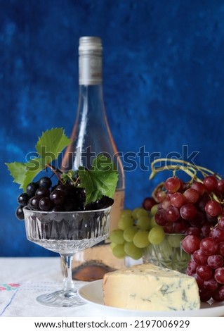 Grapes, wine and cheese on a table. Colorful summer still life on textured background with copy space.