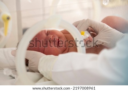 A newborn baby lies in boxes in the hospital. A child in an incubator. Neonatal and Premature Intensive Care Unit Royalty-Free Stock Photo #2197008961