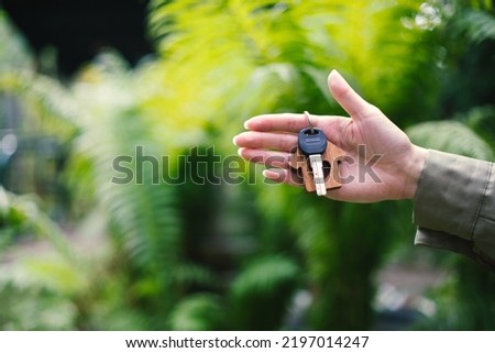 House home keys on a trinket term on young woman's family hand pale. Mortgage loan credit approved real estate tropical green summer season background copy space text template.