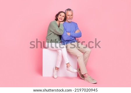 Full size photo of two peaceful idyllic partners sit podium cuddle folded arms isolated on pink color background
