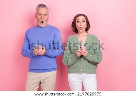 Photo of two impressed partners hold telephone stare speechless isolated on pink color background