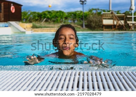 beautiful Hispanic boy playing in an outdoor pool Royalty-Free Stock Photo #2197028479
