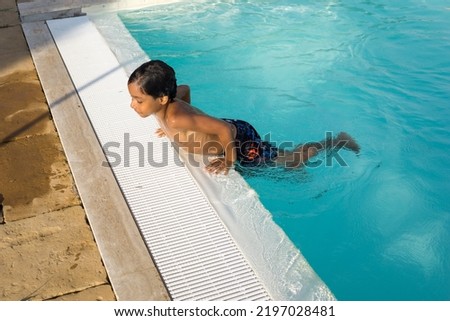 beautiful Hispanic boy playing in an outdoor pool Royalty-Free Stock Photo #2197028481