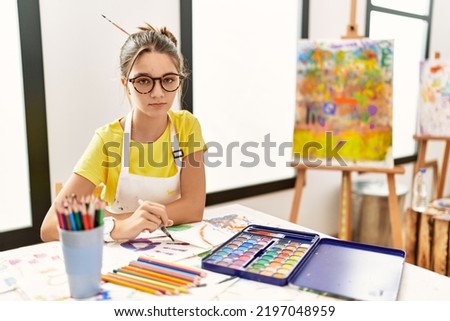 Young brunette teenager at art studio looking sleepy and tired, exhausted for fatigue and hangover, lazy eyes in the morning. 