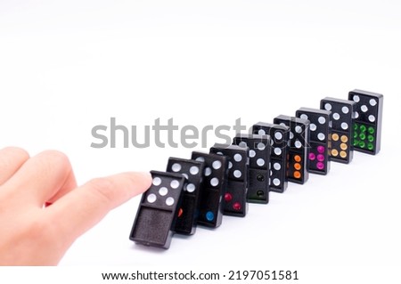 Conceptual photo of a hand starting a chain reaction with colored dominoes onthe white background of free space