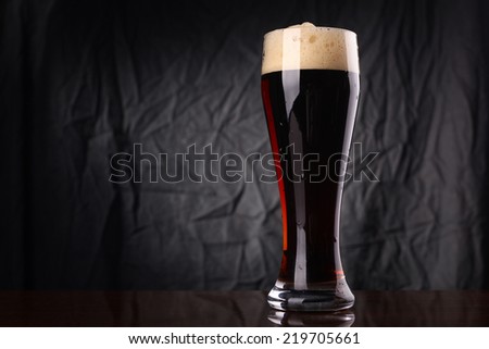 Tall glass of dark beer over a gray lit background Royalty-Free Stock Photo #219705661