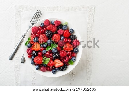 Bowl of healthy fresh berry fruit meal on white table background. Top view. Berries overhead closeup colorful assorted mix of strawberry, blueberry, raspberry, blackberry, red currant Royalty-Free Stock Photo #2197062685