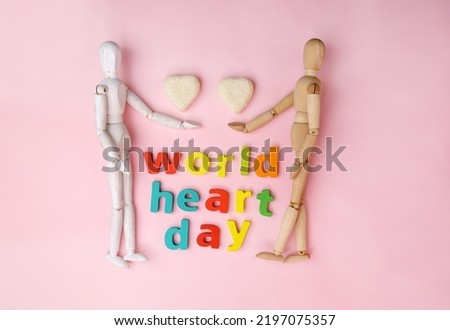World heart day, medical sign on 29th of September. Two wooden mannequins top view, pink background