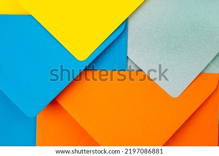 Orange, blue, yellow and silver envelopes forming a modern geometric pattern. Abstract postal backdrop design, close up. 
