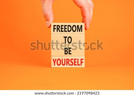 Freedom to be yourself symbol. Concept words Freedom to be yourself on wooden blocks on a beautiful orange background. Businessman hand. Business, psychological freedom to be yourself concept.