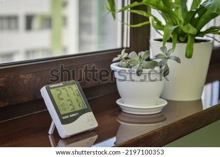 Thermometer hygrometer measuring the optimum temperature and humidity in a house on windowsill with houseplants closeup Royalty-Free Stock Photo #2197100353