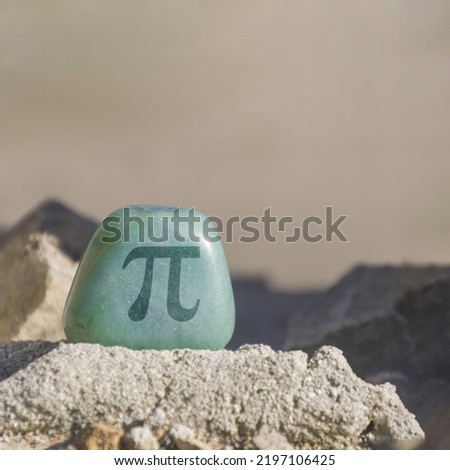Close-up shot of a stone, especially a teal colored aventurine engraved with the symbol Pi