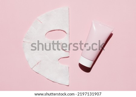 Sheet facial mask with cosmetic product on a pink background. Fabric face mask, face cream. Facial skin care at home. Royalty-Free Stock Photo #2197131907