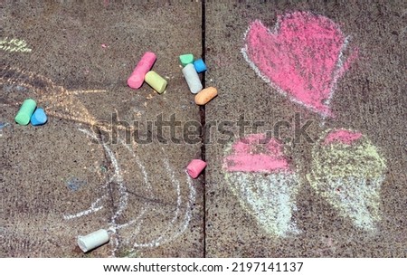 Child drawing hearts and icecreamcones 
on pawement