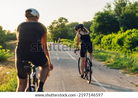 Rear view of the caucasian fit couple practicing in cycling wearing sports equipment while riding a bike outside. Concept of healthy lifestyle, sport, action, motion.Focus on a young woman.